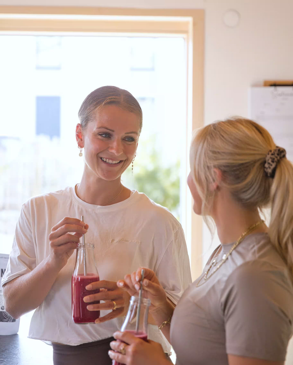 Zwei Freundinnen trinken gemeinsam einen roten Smoothie mit Kwint Mykoprotein